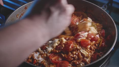 Cooking-ingredients-for-torilla-in-a-pot,-mixing-them-all-using-a-wooden-spoon,-close-up-view