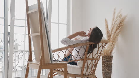 lazy woman artist waits for inspiration sitting in studio