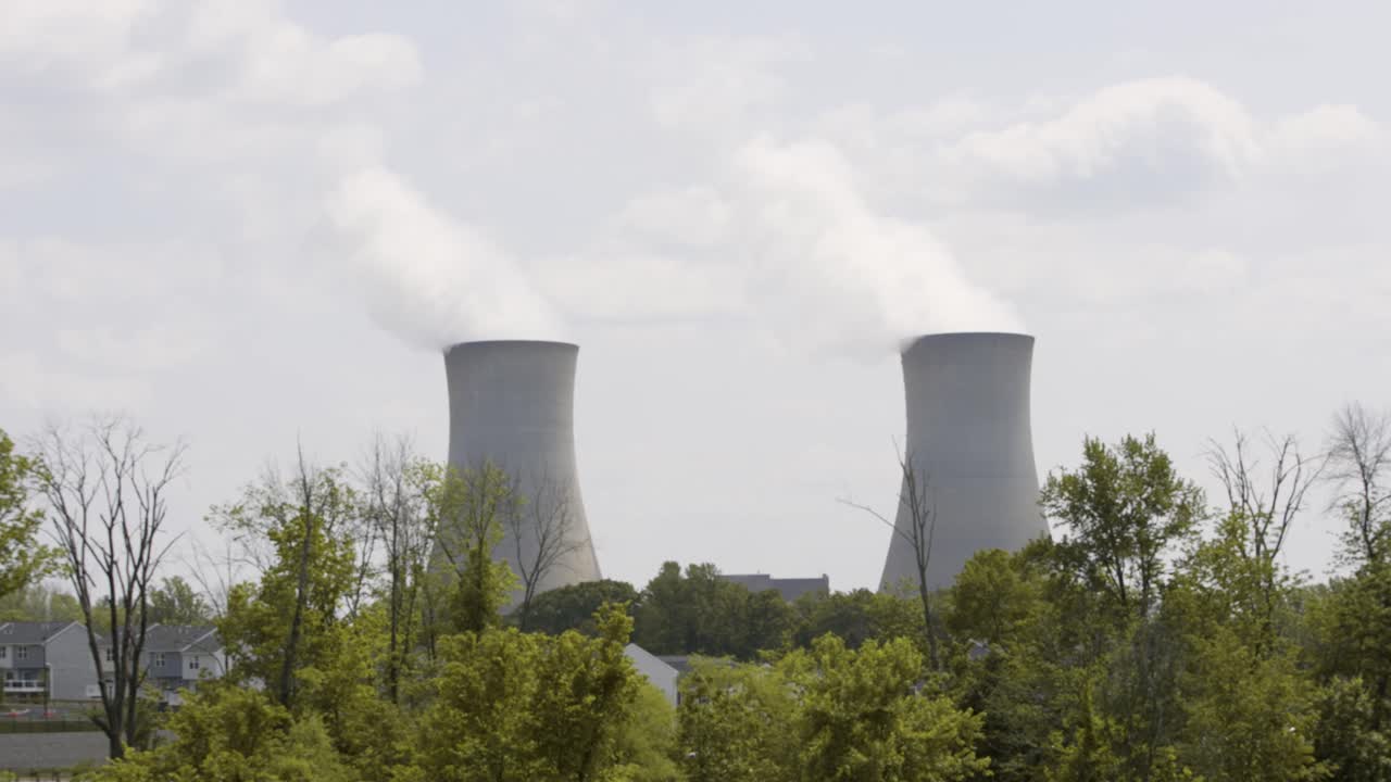 Nuclear Power Plant on a warm cloudy day with steam rising - establishing shot of industry plant