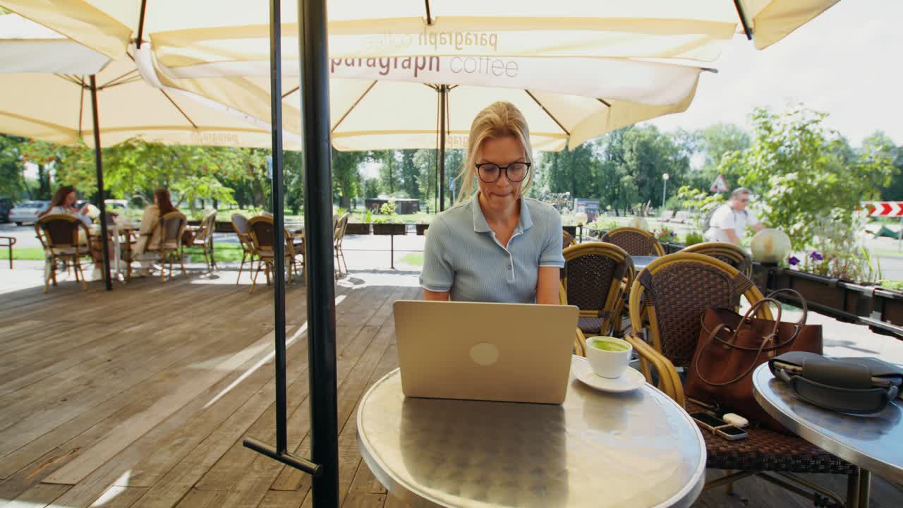 Mulher trabalhando em um café ao ar livre com laptop e café