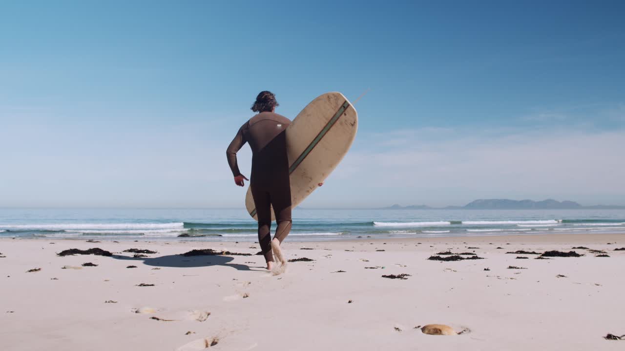 surfista corriendo con tabla de surf bajo un brazo hacia el agua