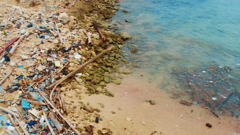 pan of trash and litter pollution strewn across beach alcove, curacao, caribbean