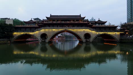 anshun bridge illuminated at night in chengdu, china over jin river - aerial drone flight