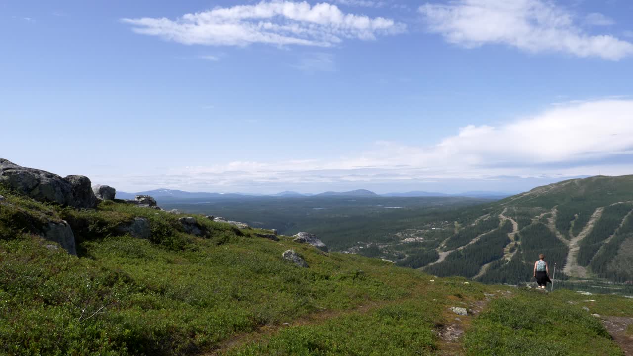 pan right shot은 한 성인 여성이 멀리서 천천히 산을 내려가는 아름다운 북극 자연 풍경을 보여줍니다.