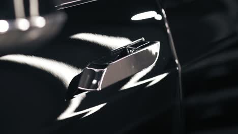 Slomotion-footage-of-chrome-tanned-door-handle-pulls-out-and-then-back-in-the-door-of-a-new-black-car.