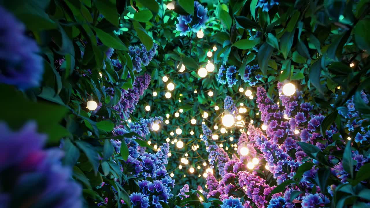 A mesmerizing upward angle captures glowing bulbs amidst vibrant purple flowers and lush greenery