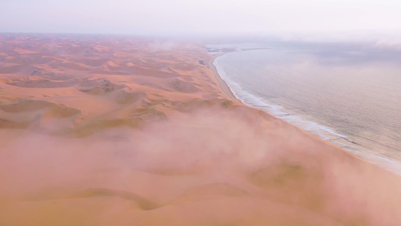 나미비아의 골격 해안을 따라 나미브 사막의 광대한 모래 언덕 위에 구름과 안개를 통해 좋은 높은 공중 샷