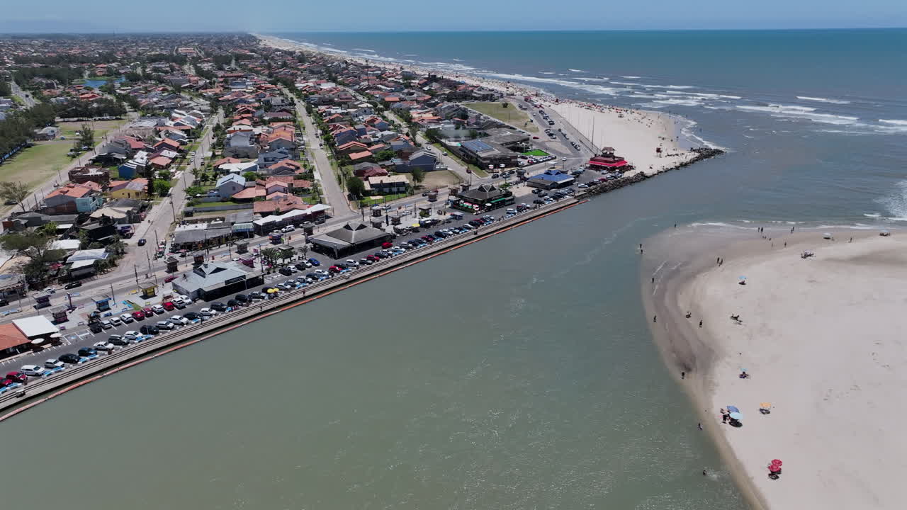 Droonin ilmakuva Tramandain joensuun infrastruktuurista, jossa on telakoituja hinaajia ja tukikohta lähellä Atlantin valtameren yhteyttä Imbessä, Brasiliassa. 4K 60fps -video