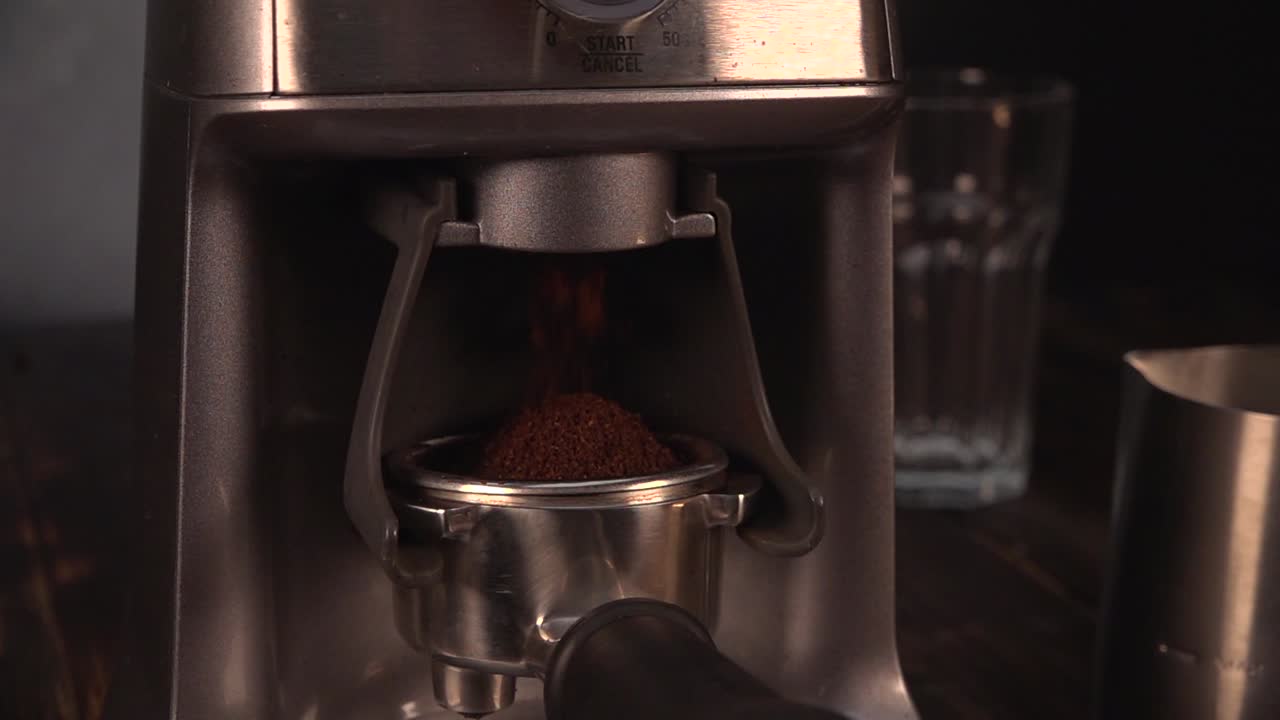 Coffee falling down a bean grinder machine at slow motion.