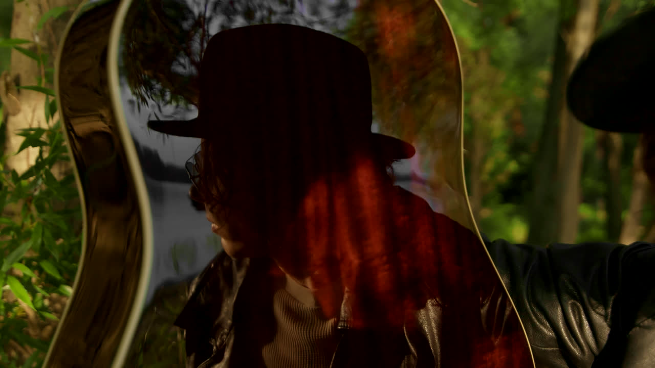 Person playing acoustic guitar in a forest