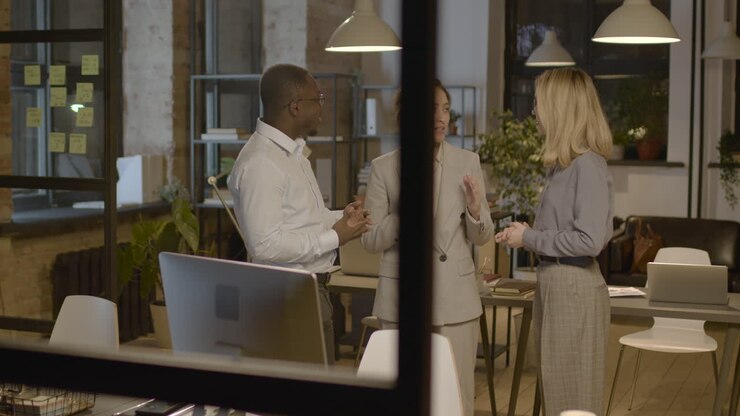 Group Of Three Employees Standing In The Office And Discussing Together About Business Strategy