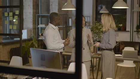 group of three  employees standing in the office and discussing together about business strategy