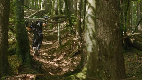 Mountain-biker-carries-his-bike-up-a-steep-gully-in-a-forest