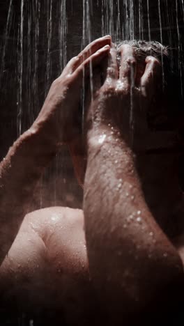 man enjoying a refreshing shower in a dimly lit space while water cascades down