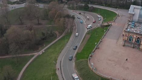 Descending-drone-shot-of-busy-narrow-road-through-alexandra-palace-London