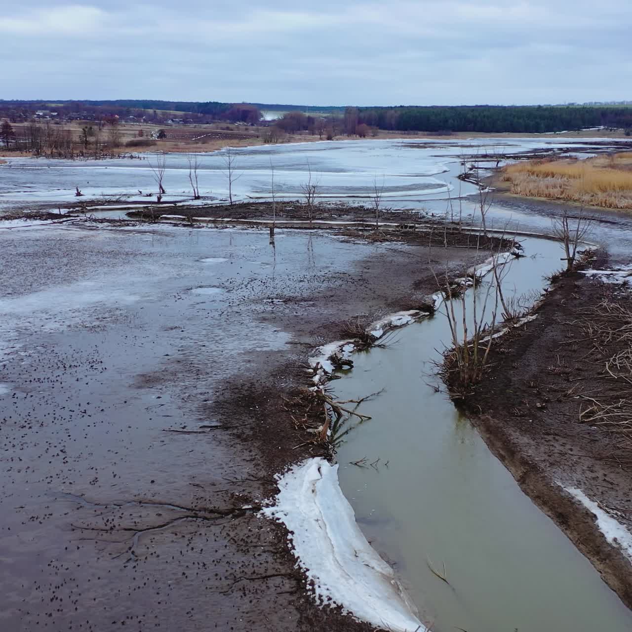Dirty river in spring. Disaster ecology in nature. Dark background of fields and river in rural place. Environmental problems