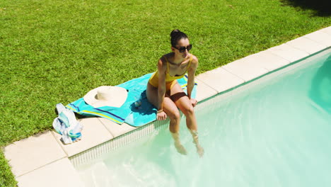 woman relaxing by pool, dipping feet in water, enjoying sunny day outdoors, copy space