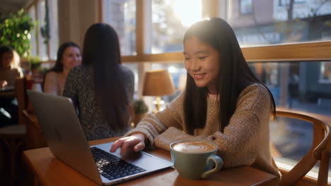 young woman working on laptop in a sunny cafe