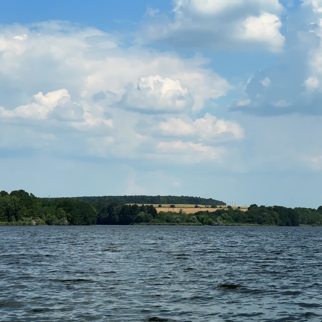 Beautiful landscape with river and fields at backdrop. Cloudy sky above the scenery