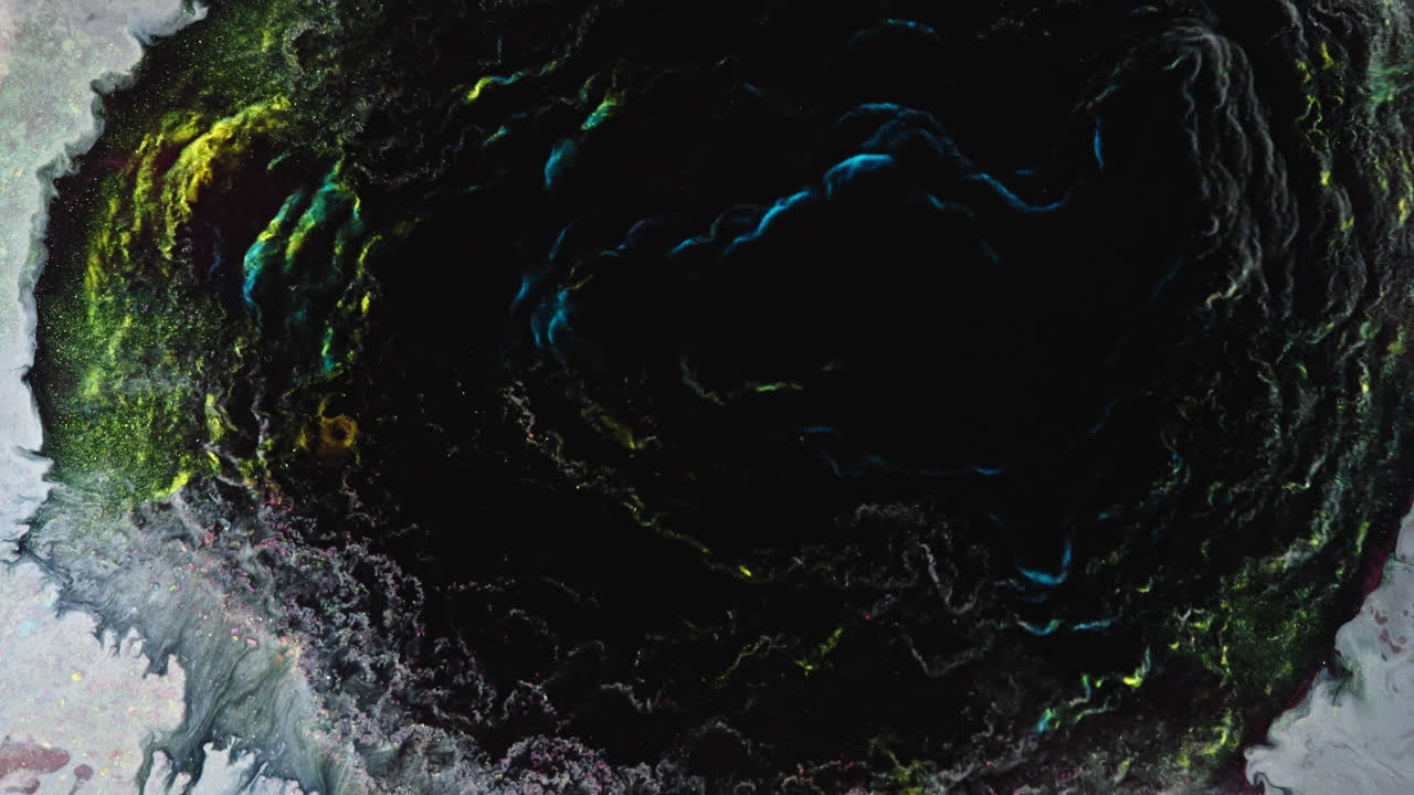 Colorful liquids blend in macro view, creating an abstract, cosmic-like pattern