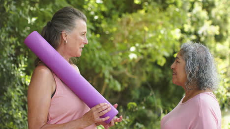 caucasian woman chats with senior biracial woman outdoors