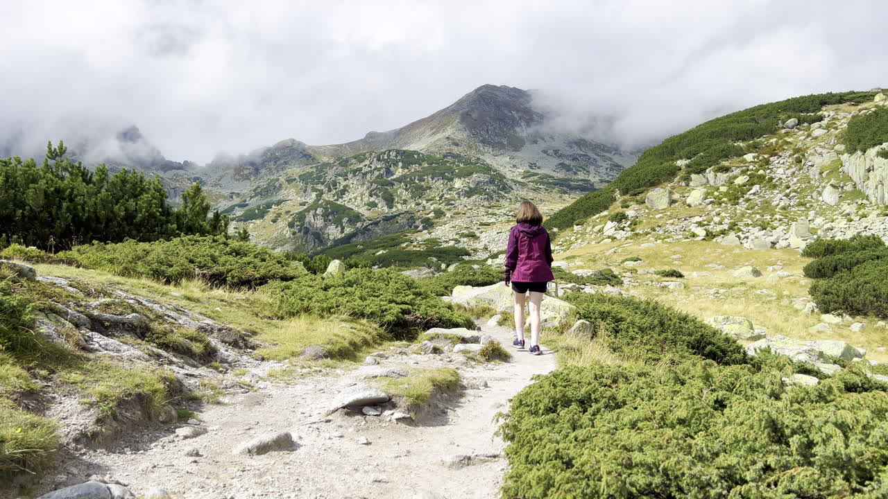una niña caminando por un sendero con enebros en las montañas retezat en rumania