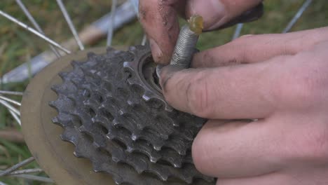 man applies the grease with his fingers and tightens the nut on the axle of the bicycle wheel