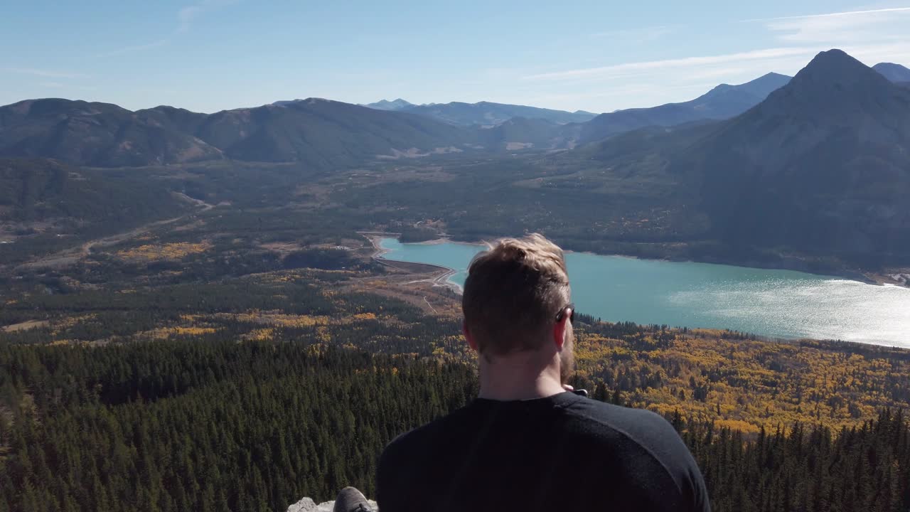Hiker taking photos on peak at Barrier Lake Kananaskis Alberta circling