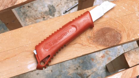 Exacto-knife-blade-placed-over-a-wooden-crafts-chair-at-a-carpenter-workshop-outdoors-during-the-day-in-a-hot-summer-day-shot-from-above-spinning-around