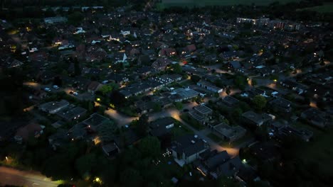 drone flight over dark american city with lighting lantern and headlights of car in street. top down. housing area with homes at dusk. spring season in quiet neighborhood.