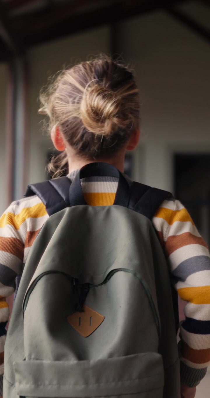 Young Child With Backpack Walking Towards School Entrance