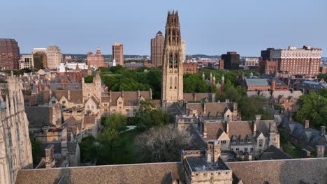 Aerial flyover Yale University campus in New Haven, Connecticut, with Georgian-style dormitory, Gothic spires and the city skyline under clear summer sky. Wide shot. Small American city