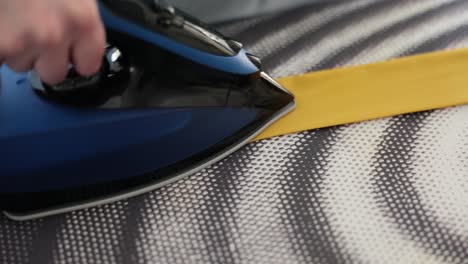 close-up of a hand ironing yellow fabric