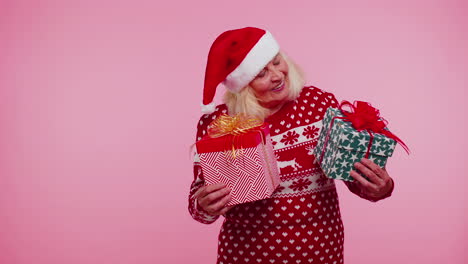 Grandmother-in-Santa-sweater-presenting-one-Christmas-gift-box,-stretches-out-his-hands-to-camera