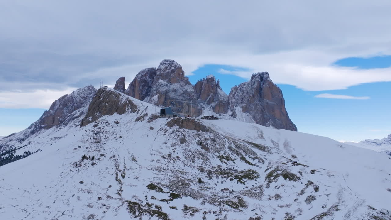 이탈리아 알프스의 산 꼭대기에 있는 스키 리프트 주위에서 회전하는 공중 영상입니다.