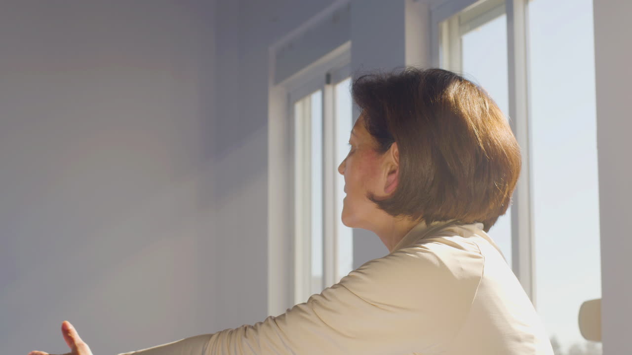 체육관 에서 손 으로 느린 태극권 운동 을 하는 고령 여성