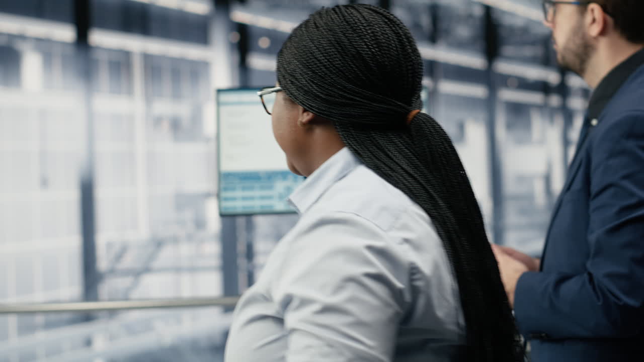 Donna e collega che monitorano linee di produzione automatizzate di semiconduttori.