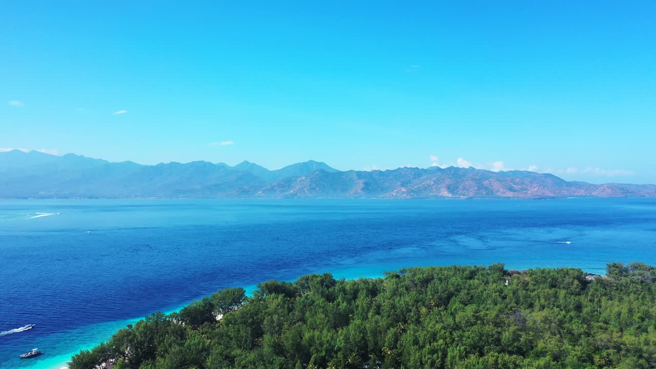 인도네시아의 무성한 섬 - 푸른 하늘 아래 아름다운 산을 바라보는 깊고 푸른 바닷물로 둘러싸인 푸른 나무들의 열대 낙원 - 와이드 샷