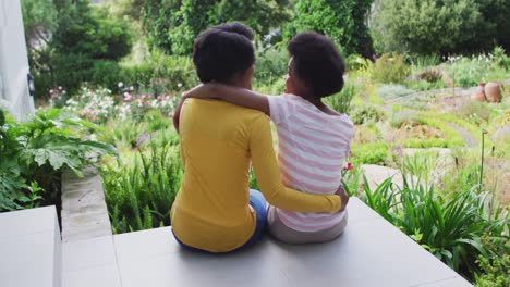 happy african american mother and daughter embracing in garden