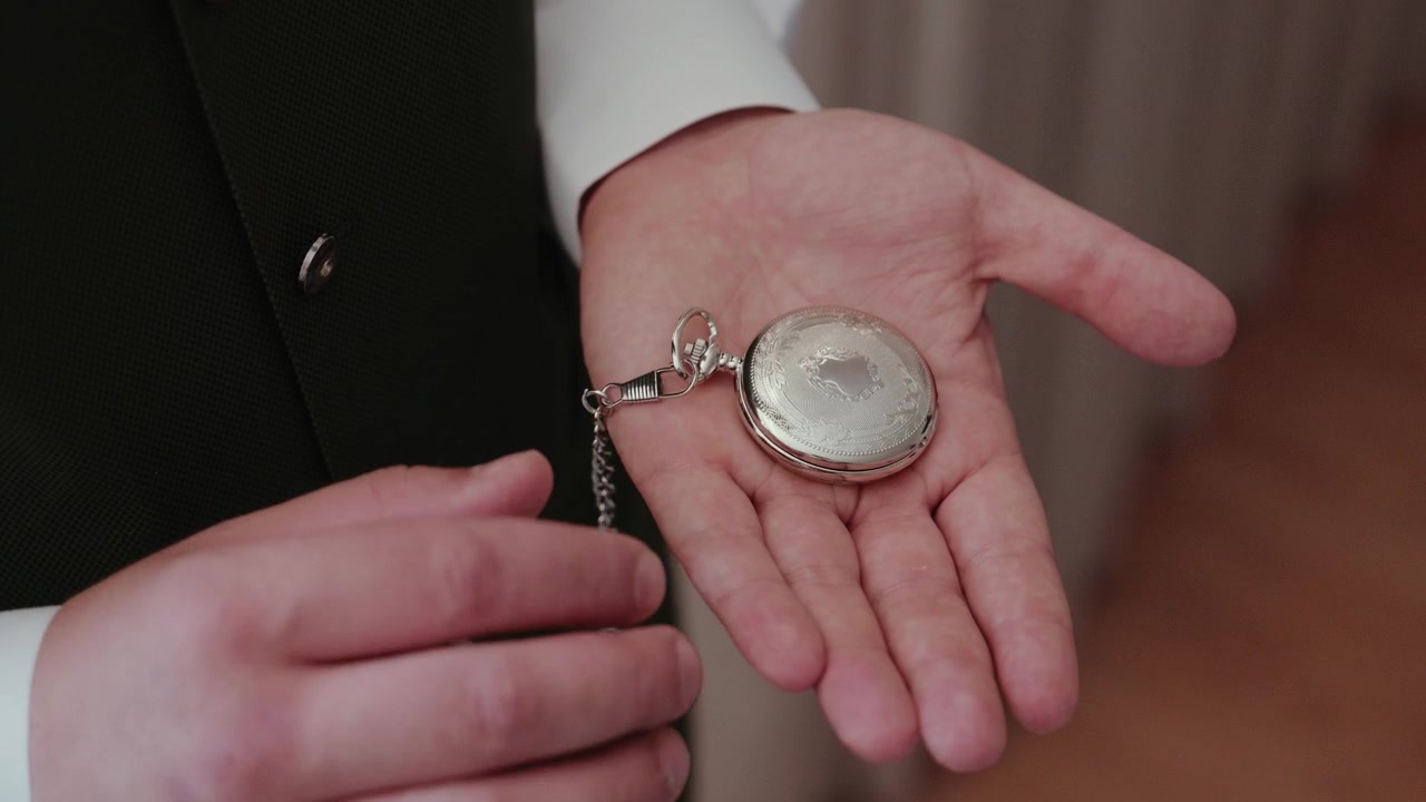 Person's hand displaying an antique silver pocket watch with an open lid, symbolizing time, history, and precision