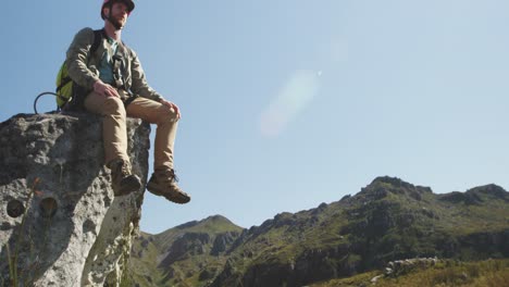 young caucasian man sitting on a rock