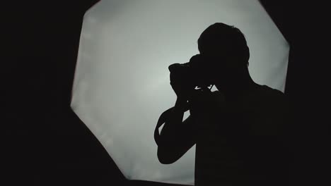 Photographer-is-taking-pictures-in-the-studio-on-a-soft-box-background-close-up-silhouette