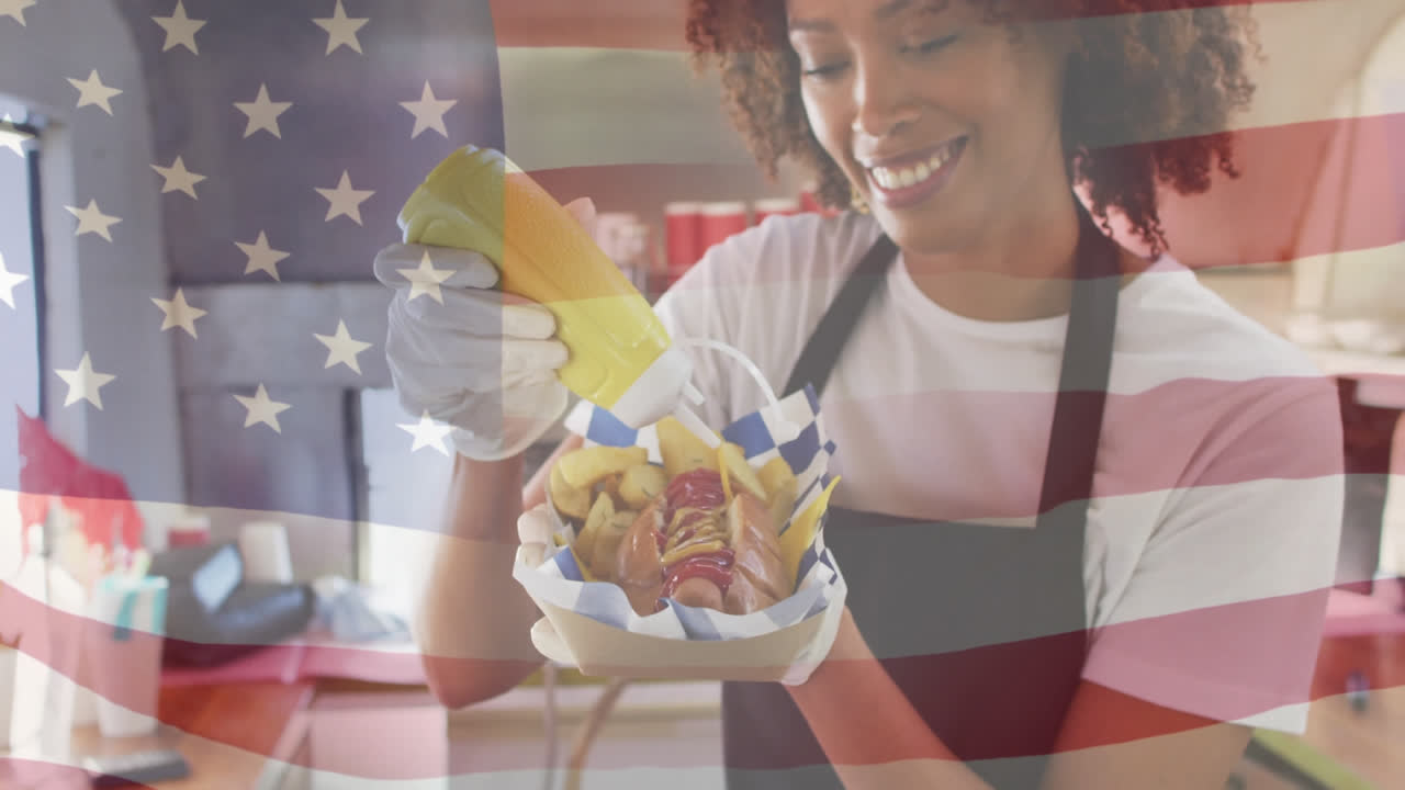 compuesto de una mujer afroamericana sonriente preparando un perrito caliente, y agitando la bandera estadounidense