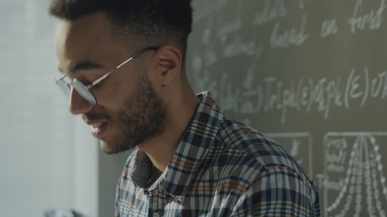 Young Man Studying Mathematical Equations on a Chalkboard