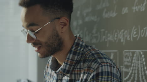 young man studying mathematical equations on a chalkboard