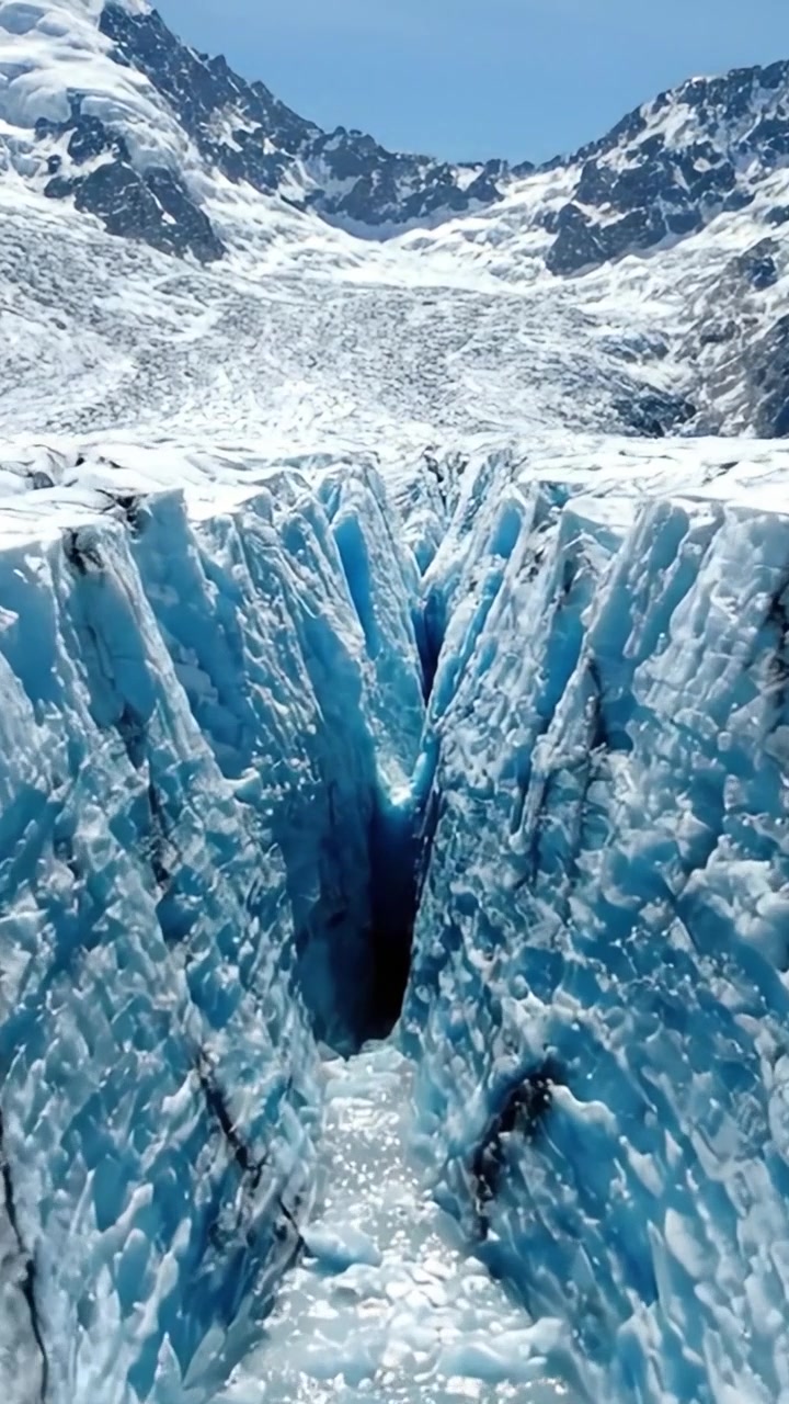 Impresionante grieta glacial: Vistas cautivadoras de formaciones de hielo y cristales azules irregulares en un majestuoso paisaje nevado bajo un cielo azul brillante.