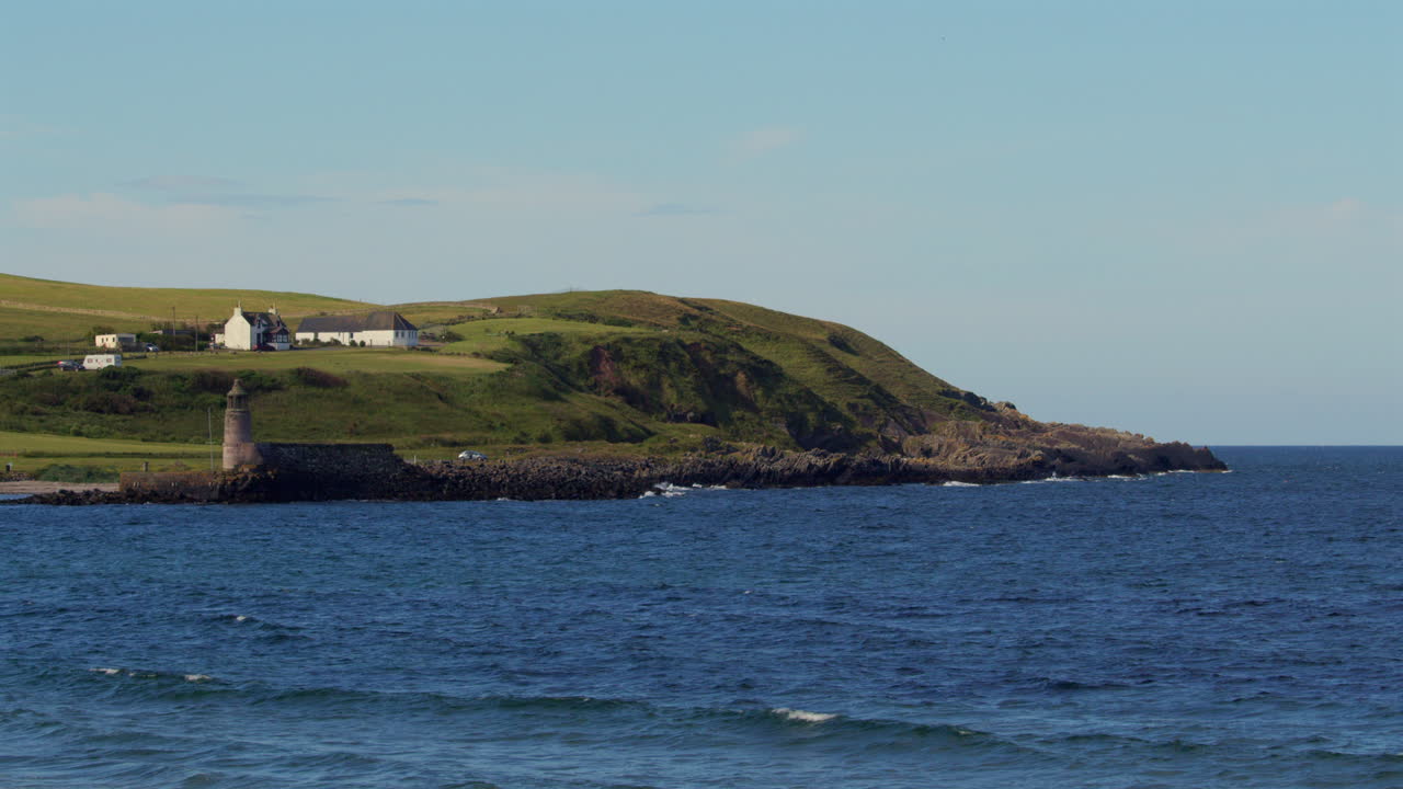 Extra wide shot of port Logan old lighthouse and harbour with buildings in background