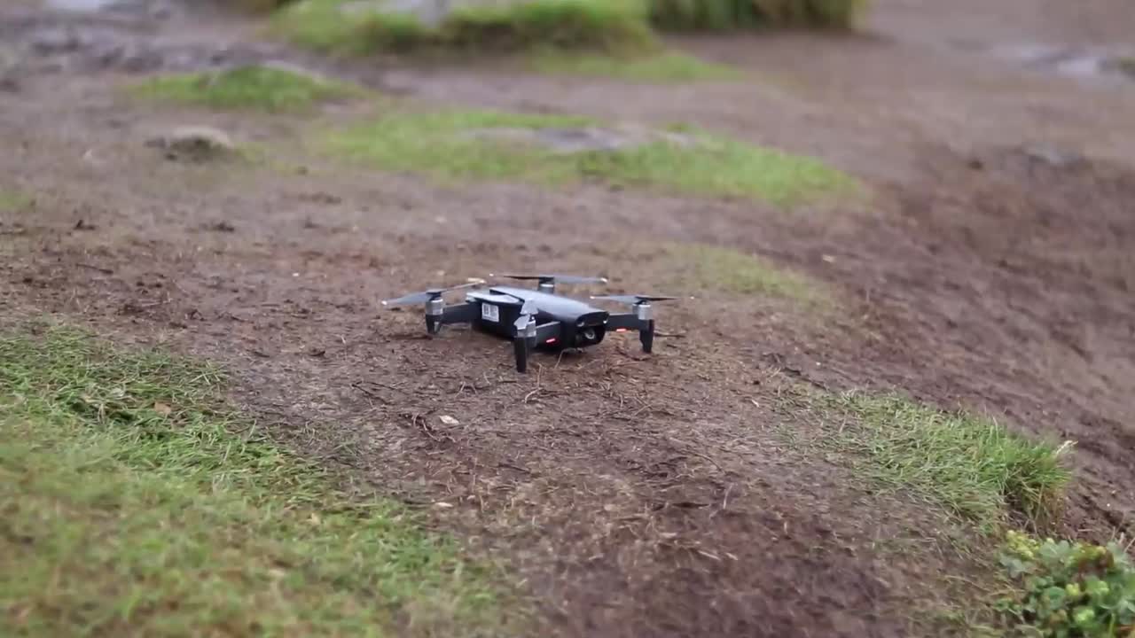 등산복을 입은 남자가 이륙하기 위해 땅에 검은색 드론을 싣고 있다