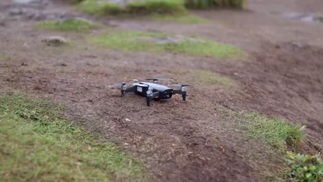 a man in hiking clothing putting a black drone on the ground to take off