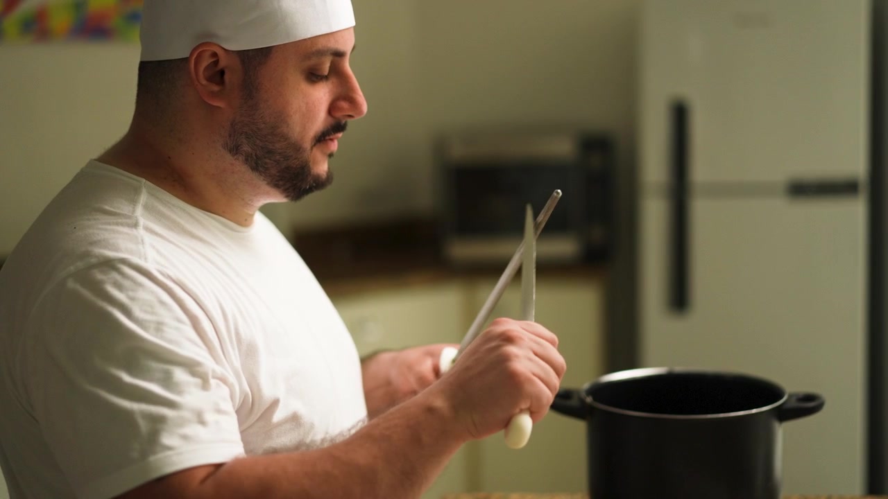 Un cuoco affila un coltello in una cucina professionale